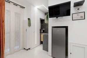 Una cuina moderna amb frigorífic integrat, un televisió de pantalla plana penjada sobre la barra i una porta corredissa que dona a una altra estança.