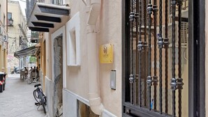 Una calle estrecha flanqueada por edificios, una bicicleta estacionada en la acera y una reja negra con un letrero.