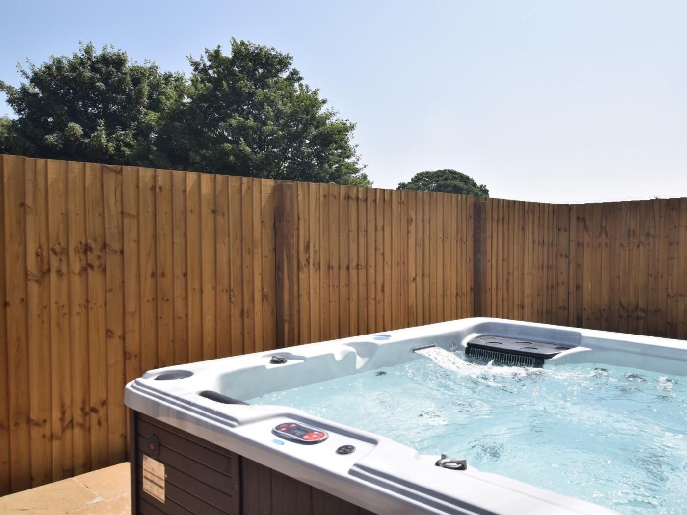 A hot tub with a wooden fence in the background.