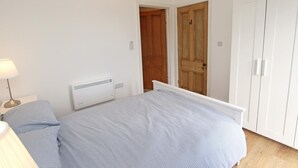 Un dormitorio con cama, lámpara de noche, calefactor y armario.