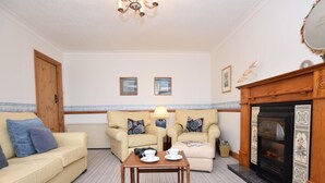 Una sala de estar acogedora con un sofá, sillones, una mesa de centro y una chimenea.