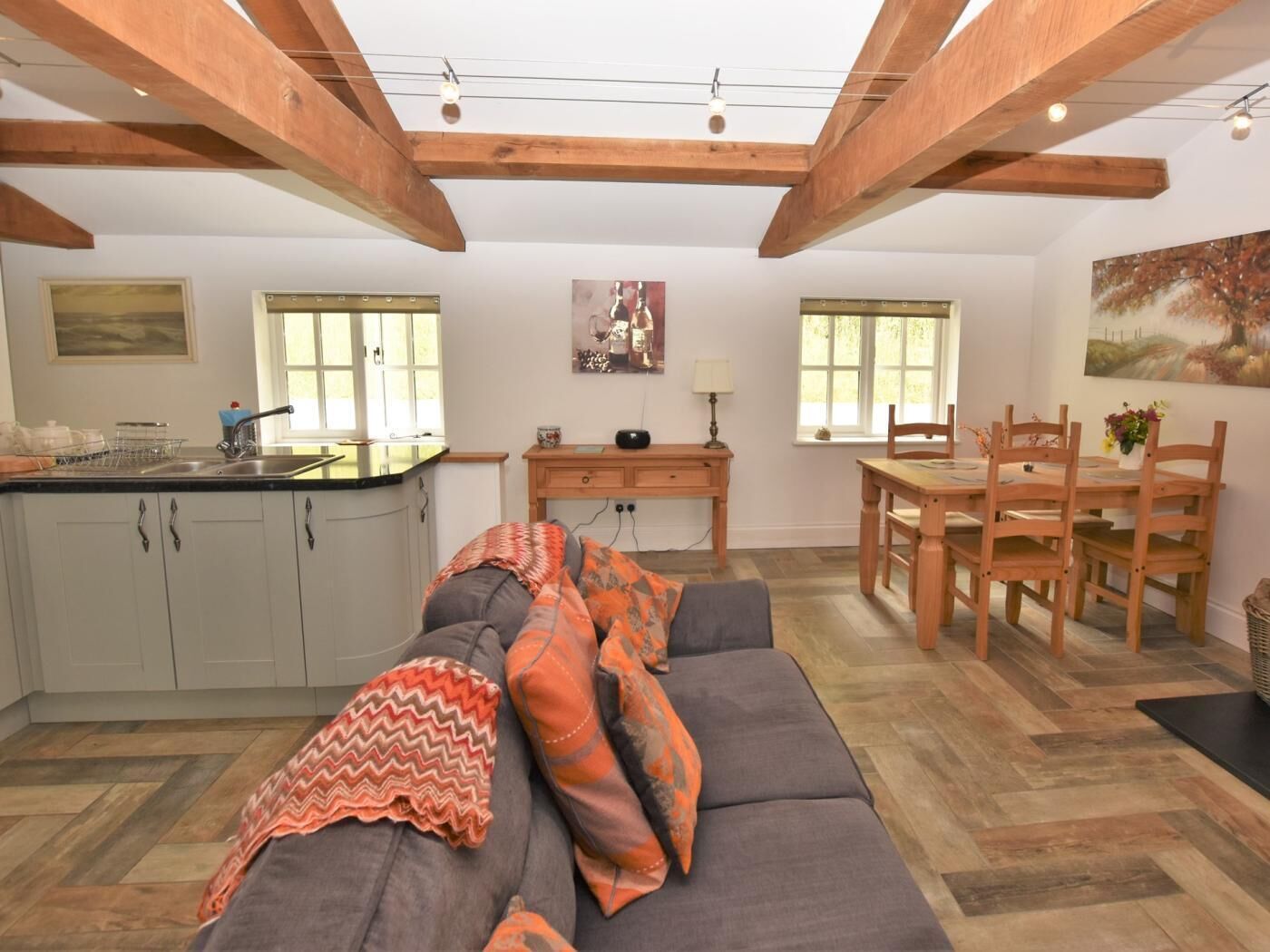Een ruime woonkamer met een bank, eettafel en keuken.