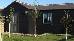A dark-colored building with a door, a window, and a small tree in the yard. - 1 Bed in Belford (oc-cn008) (Adderstone with Lucker)