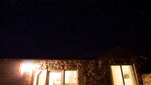 A stone building with a large glass door leading to an interior space, under a starry night sky. - 1 Bed in Belford (oc-cn008) (Adderstone with Lucker)