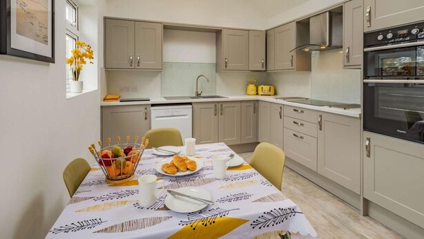Una cocina moderna con una mesa de comedor dispuesta para el desayuno, un tragaluz y un horno empotrado.