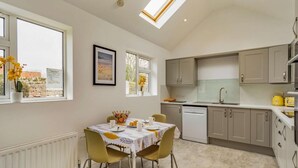 Una cocina moderna con comedor, que incluye una mesa con sillas, un ventanal y un tragaluz.