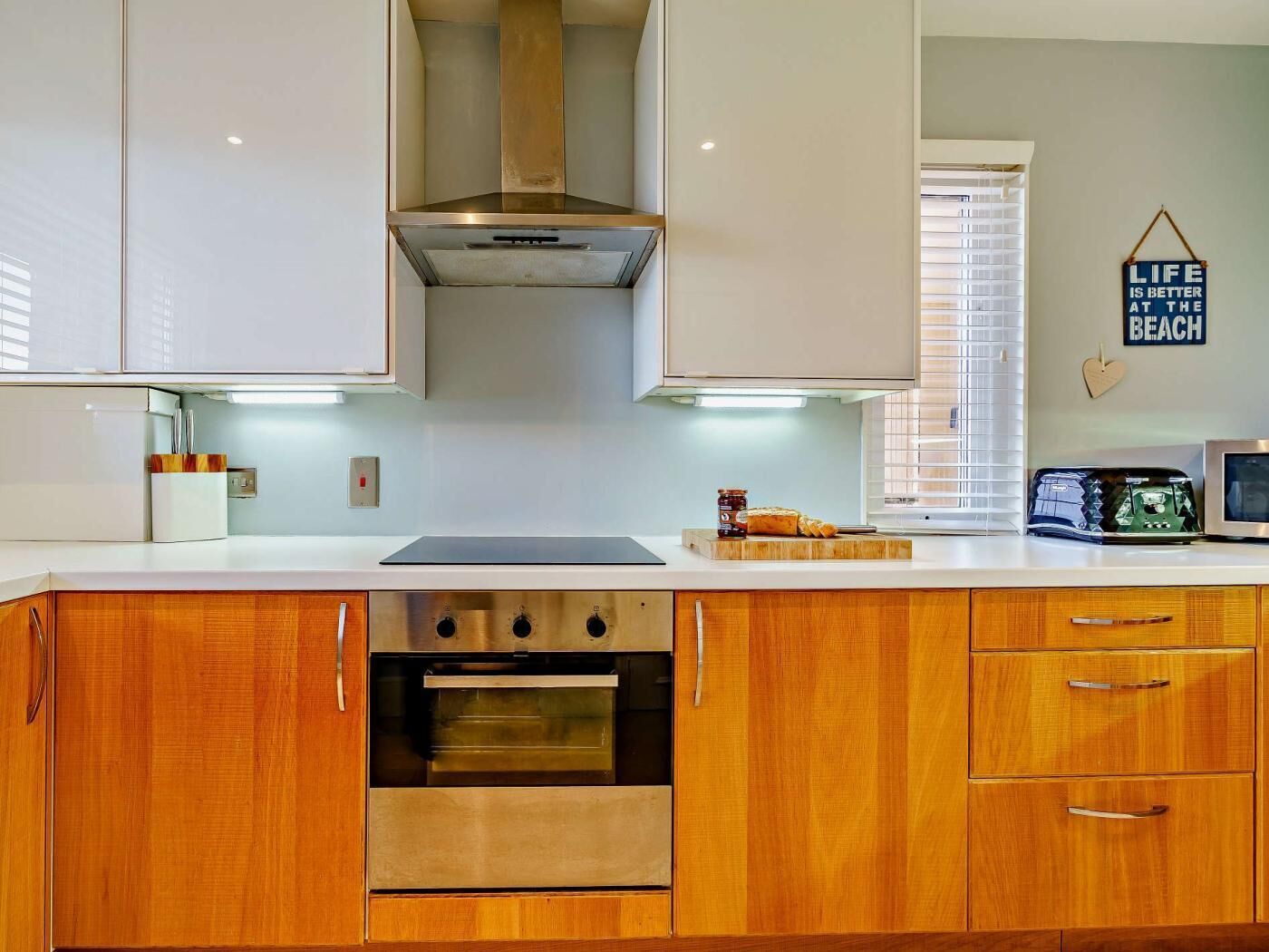 Une cuisine moderne avec des meubles en bois, un four en acier inoxydable et un micro-ondes encastré.