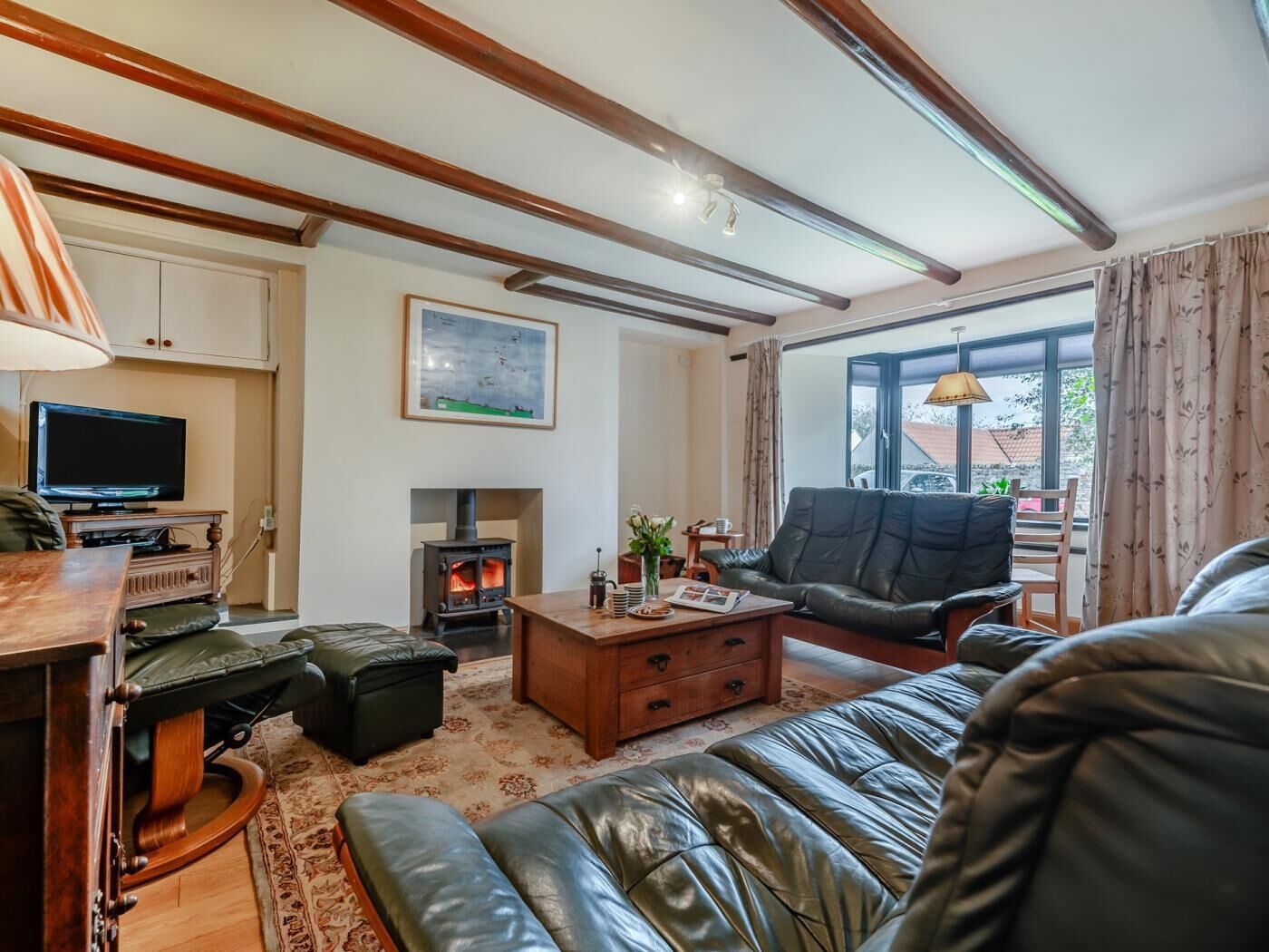 A cozy living room with a fireplace, leather sofa, wooden coffee table, and a television.