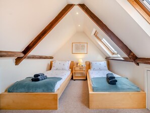 A small, cozy attic bedroom with two wooden beds, a skylight, and a framed picture on the wall. - 3 Bed in Berwick-upon-tweed (oc-cn040) (Holy Island)