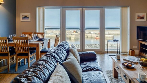 Ein Wohnzimmer mit Sofa, Esstisch, Stühlen und Fernseher.