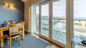 Ein Essbereich mit Tisch für vier Personen, Blick auf eine Brücke und ein Balkon mit Glasüren.