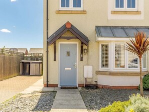 A two-story building with a grey door, a small porch, and a window with a grid pattern. - 3 Bed in Beadnell (oc-cn042) (Beadnell)