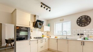 Una cocina moderna con horno empotrado, un lavamanos y un reloj en la pared.