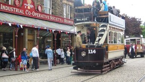 A tram with the number 114, passengers boarding and alighting, and a building with a sign reading 'Industrial Co-Operative Society Ltd.' - 1 Bed in Riding Mill (oc-cn063) (Corbridge)