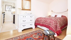 A bedroom with a bed, a dresser, a mirror, a small table with a book, and a patterned rug. - 1 Bed in Riding Mill (oc-cn063) (Corbridge)