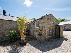 A stone building with a gravel driveway, a potted plant, and a small door. - 1 Bed in Riding Mill (oc-cn063) (Corbridge)