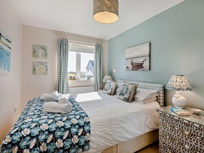 A bedroom with a bed, a nightstand, a window with curtains, and wall art. - 3 Bed in Seahouses (oc-cn064) (Seahouses)