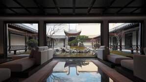 Ein traditioneller japanischer Innenraum mit Tatami-Böden, einem Koiteich und Blick auf einen traditionellen Garten.
