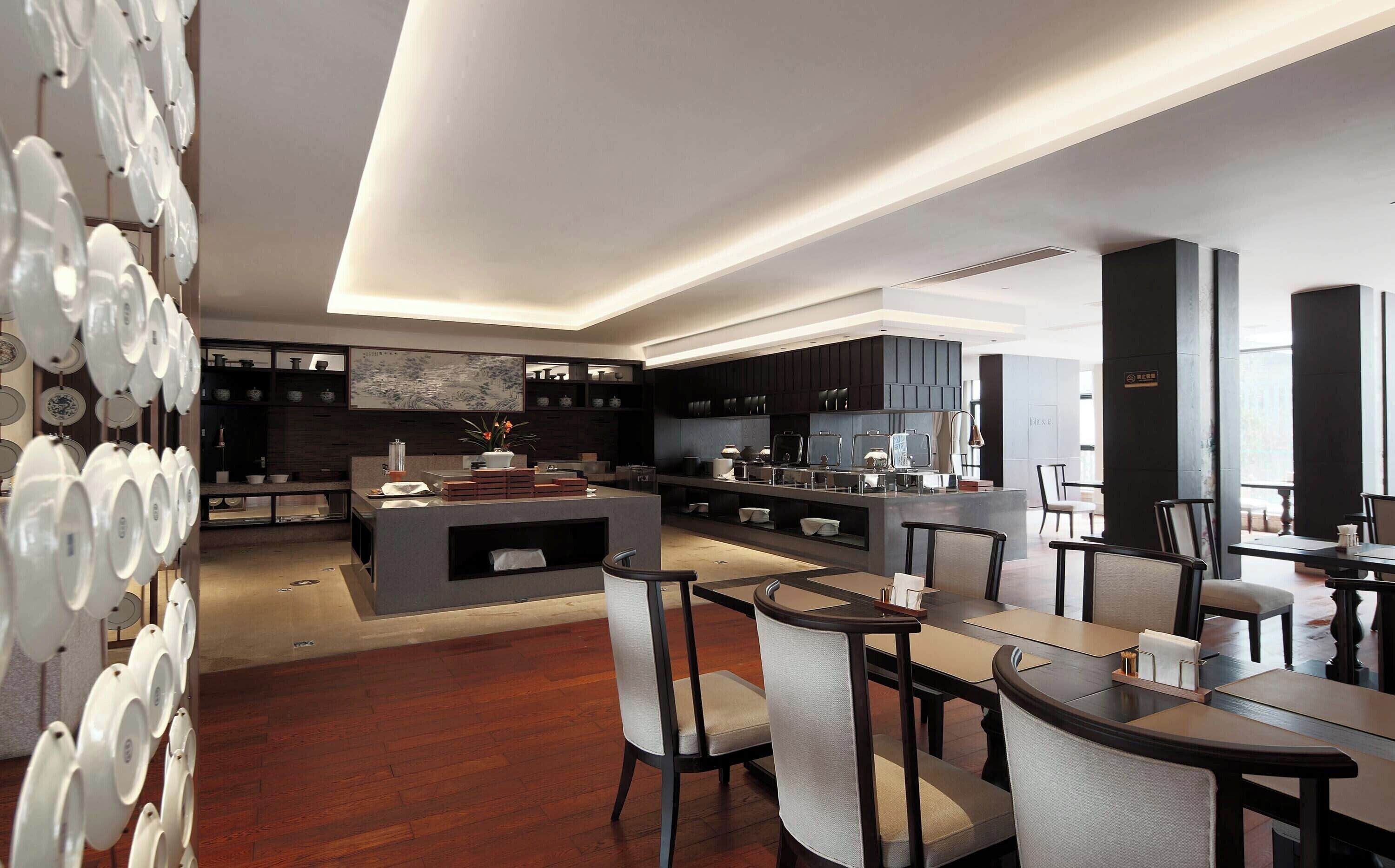 Una cocina moderna con una isla central, muebles oscuros y un comedor con sillas y una mesa.