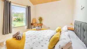 Une chambre à coucher avec un lit, un bureau, une chaise et une fenêtre avec des rideaux.