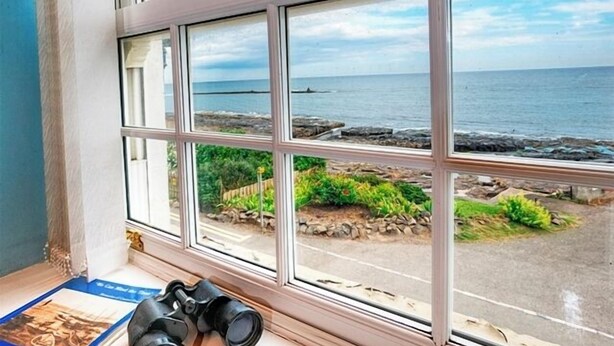 Ett fönster med utsikt över havet och en väg.