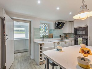 A modern kitchen with a central island, built-in oven, and a window with a view. - 2 Bed in Alnwick (oc-cn096) (Dunstan)