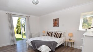Une chambre à coucher comprenant un lit, deux lampes de chevet, un radiateur, une fenêtre et une porte donnant sur un balcon.