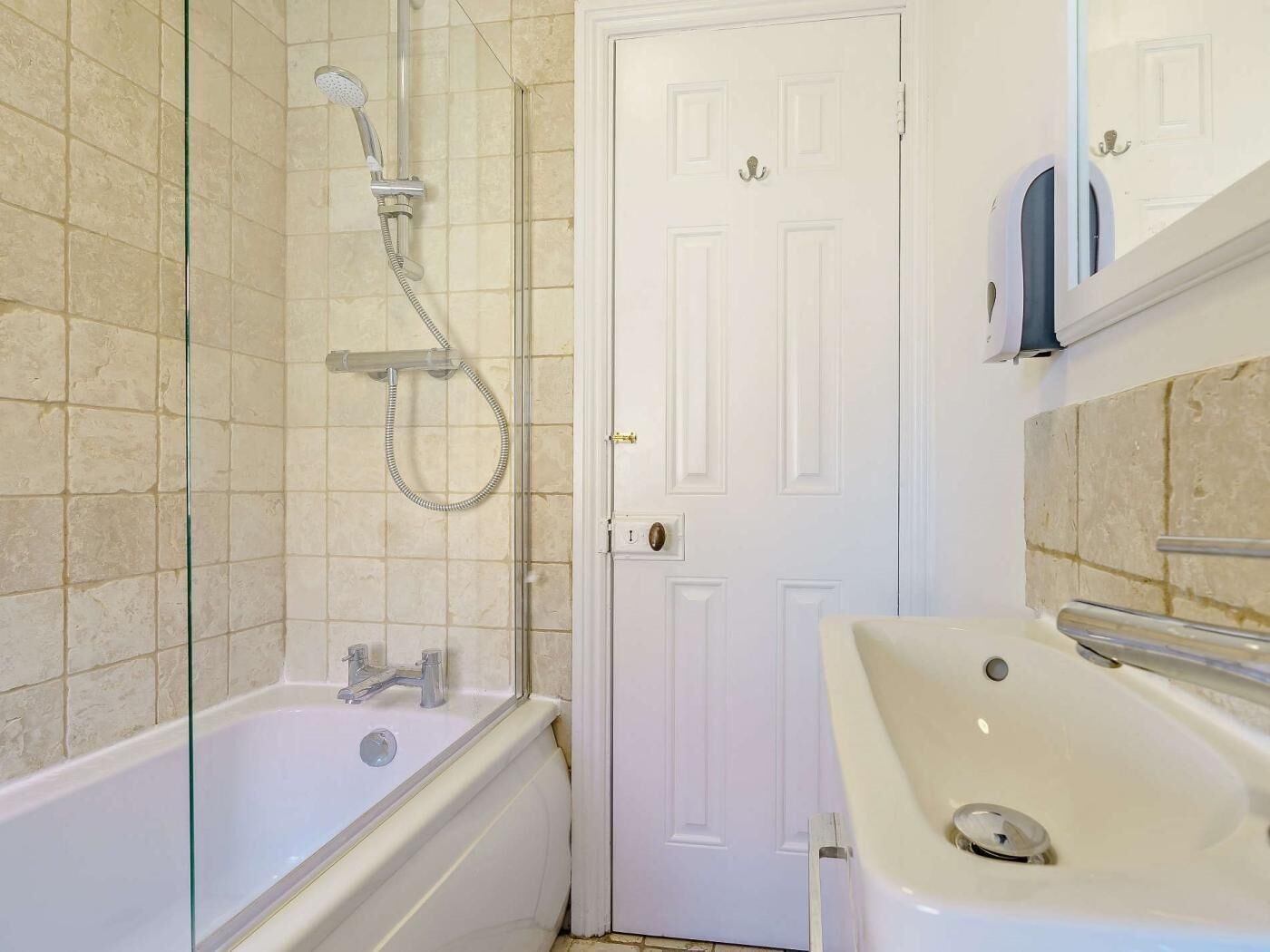 Un bagno con doccia vetrata, una vasca da bagno bianca e un lavandino con specchio sopra.
