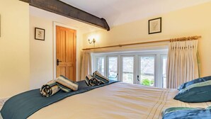 A bedroom with a large bed, a wooden door, a window with curtains, and a wall-mounted light fixture. - 4 Bed in Consett (oc-cn108) (Hunstanworth)
