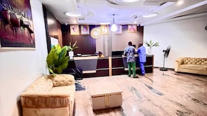 A lobby with a reception desk, seating area, and a large plant.