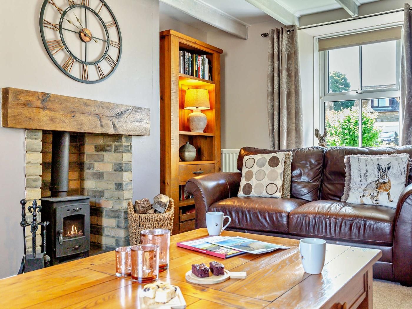A cozy living room with a fireplace, leather sofa, and a bookshelf.