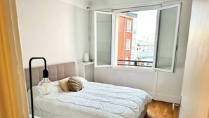 A bedroom with a bed, a window, a radiator, and a small rug. - Celine 8 (Paris)