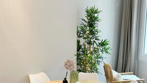 A round dining table with white chairs, a small plant, and a tray with a cup and a candle. - Celine 8 (Paris)