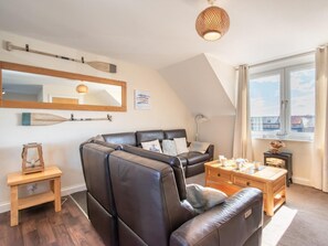 Ein modernes Wohnzimmer mit einem Ecksofa, einem kleinen Holztisch, einem Kamin und einem großen Fenster mit Blick.