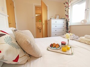 Ein Hotelzimmer mit einem Bett, einem Nachttisch mit einem Tablett mit Croissants, Orangensaft und einer Blumenkomposition.