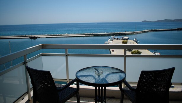 A balcony with two chairs and a table, overlooking a calm sea and a pier. - Hotel ALS Karystos (Karystos)