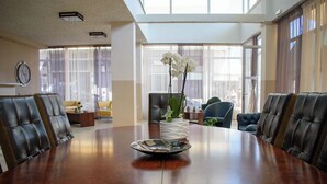 A conference room with a large table, chairs, a clock, and a window with curtains. - Hotel ALS Karystos (Karystos)