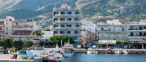 A coastal town with a marina, buildings, and wind turbines in the background.