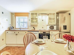 A kitchen with white cabinets, a microwave, an oven, and a dining table set for two. - 3 Bed in Consett (oc-cn110) (Hunstanworth)
