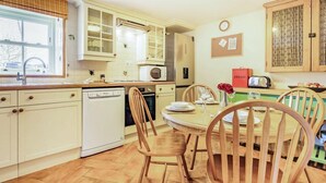 Une cuisine équipée d’un lave-vaisselle, d’un four à micro-ondes et d’une table à manger pour quatre personnes.