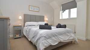 A bedroom with a bed, bedside lamps, a nightstand, a radiator, and a window. - 2 Bed in Seahouses (oc-cn135) (Seahouses)