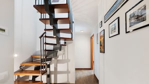 A modern interior with a spiral staircase, wooden flooring, and framed artwork on the walls.