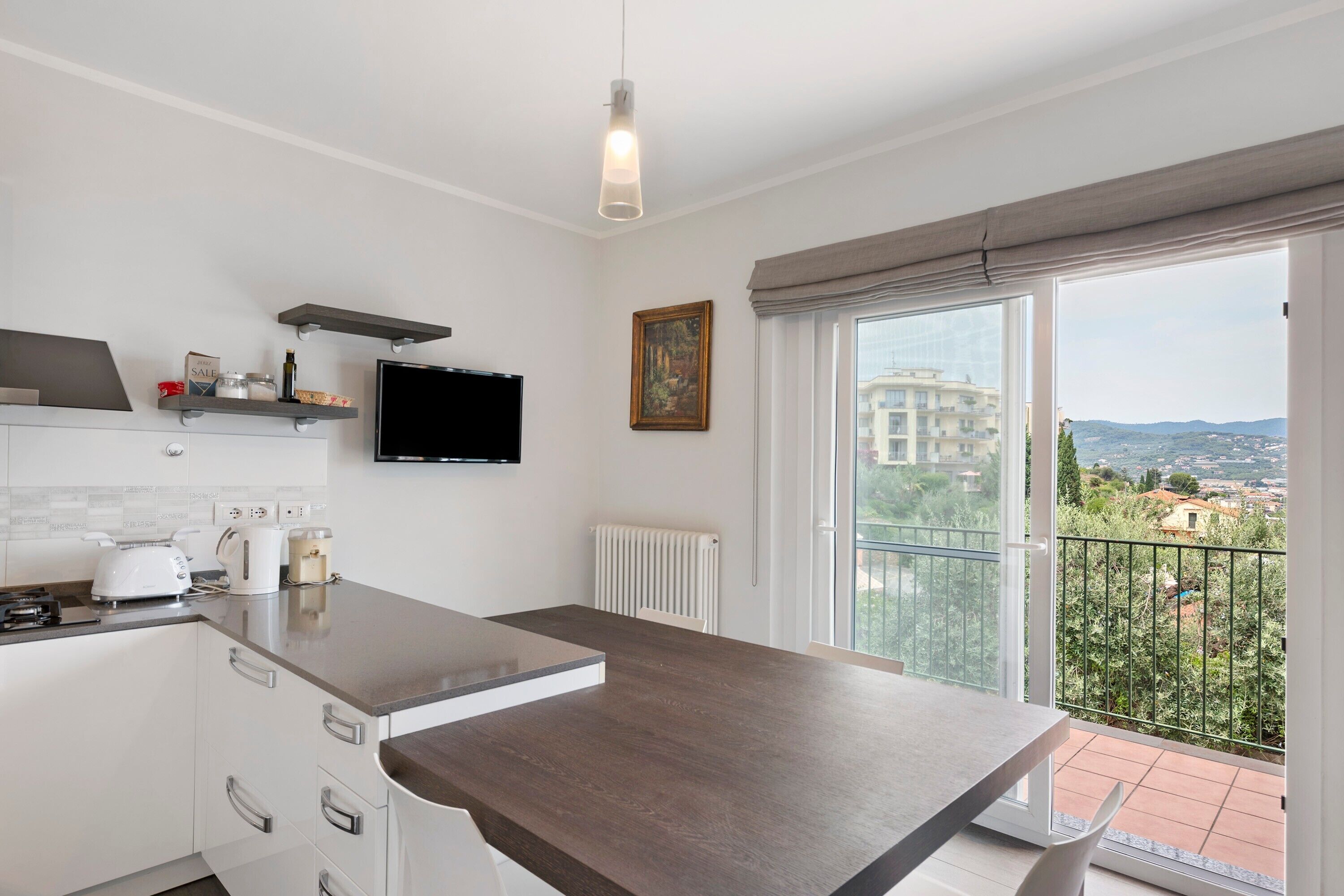Une cuisine moderne dotée d’un grand îlot central, d’un téléviseur à écran plat et d’un balcon offrant une vue sur la ville.