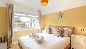 Una habitación de hotel con cama, mesita de noche, lámpara, decoración con forma de estrella y ventana con cortinas.