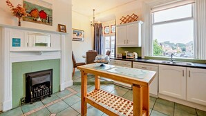 A kitchen with a fireplace, a dining table, and a view of the city. - 5 Bed in Tynemouth (oc-cn125) (Tynemouth)