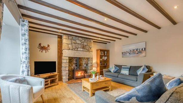 A cozy living room with a stone fireplace, a television, a sofa, and a bookshelf. - 3 Bed in Seahouses (oc-cn103) (Seahouses)