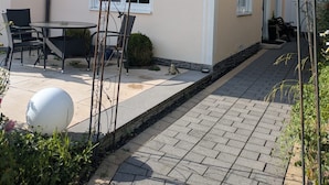 A building with a paved patio, outdoor seating, and a metal archway. - Vacation rental, comfortable and modern, designed for discerning guests, near the main train station (Freudenstadt)