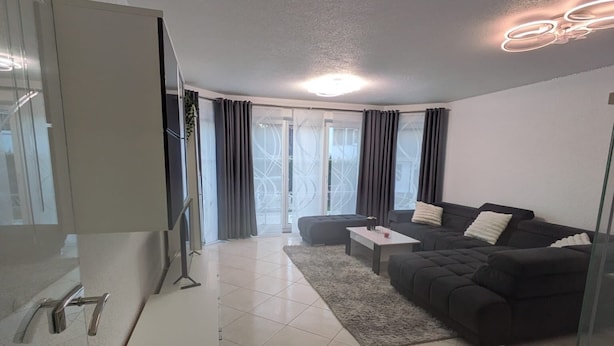 A modern living room with a sofa, a coffee table, and a TV. - Vacation rental, comfortable and modern, designed for discerning guests, near the main train station (Freudenstadt)
