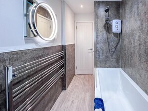 A bathroom with a bathtub, a shower, a vanity with a mirror, and a towel rack. - 2 Bed in Beadnell (oc-cn147) (Beadnell)