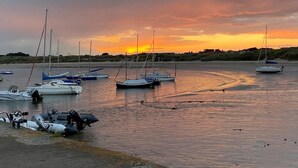 Ein Yachthafen mit vertäuten Booten, ruhigem Wasser und einem Sonnenuntergang im Hintergrund.